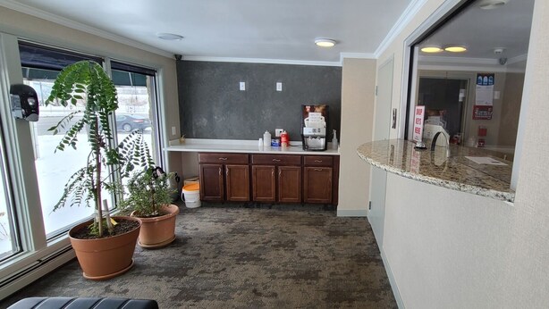 A compact kitchen with wooden cabinets, a granite countertop, and a large window offering a view of the street.