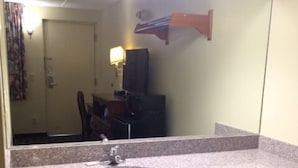 A bathroom with a granite countertop sink, a mirror, and a dark patterned floor.
