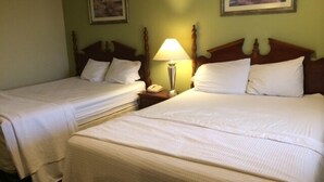 A hotel room with two single beds, a bedside table with a lamp, and a painting on the wall.