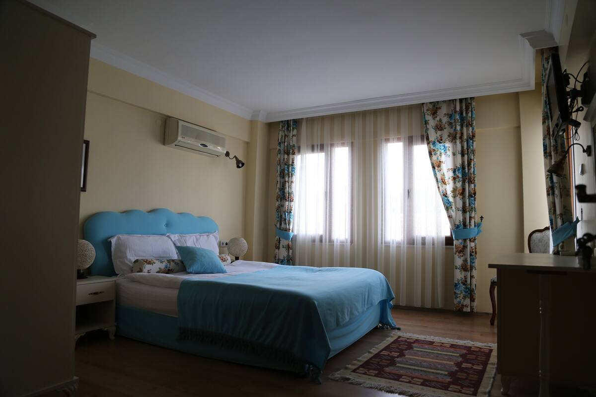 Un dormitorio con cama, mesita de noche, cómoda y ventana con cortinas.