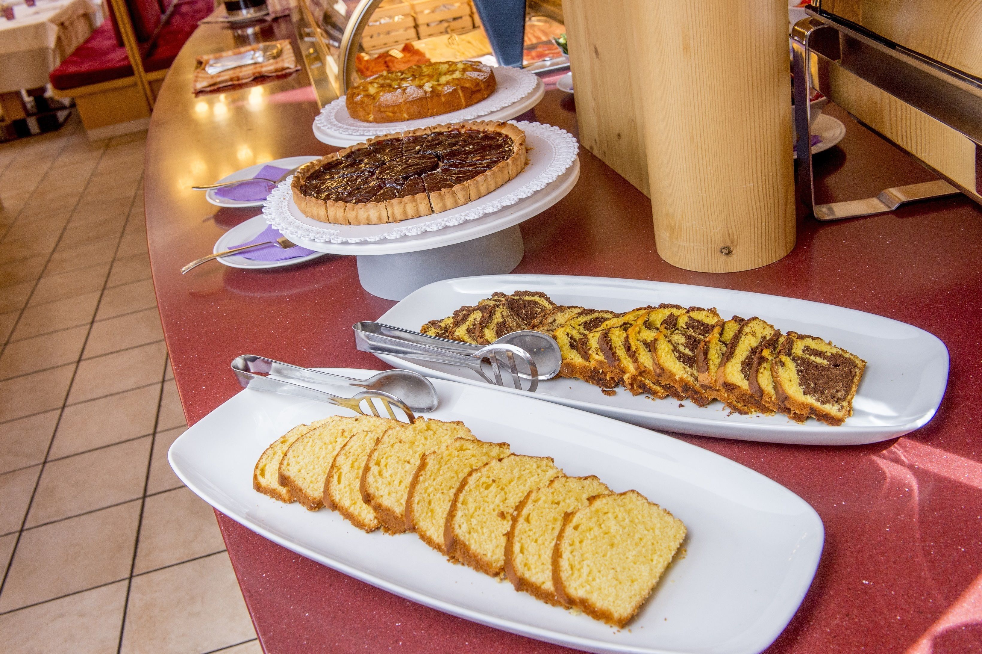 A buffet table with various desserts including cakes and pastries.