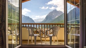 A balcony with two white plastic chairs, a glass door, and a mountain view. - Albergo Alla Rosa (Canazei)