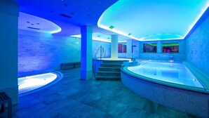 A modern spa with a curved hot tub, a staircase, and a glass wall. - Albergo Alla Rosa (Canazei)
