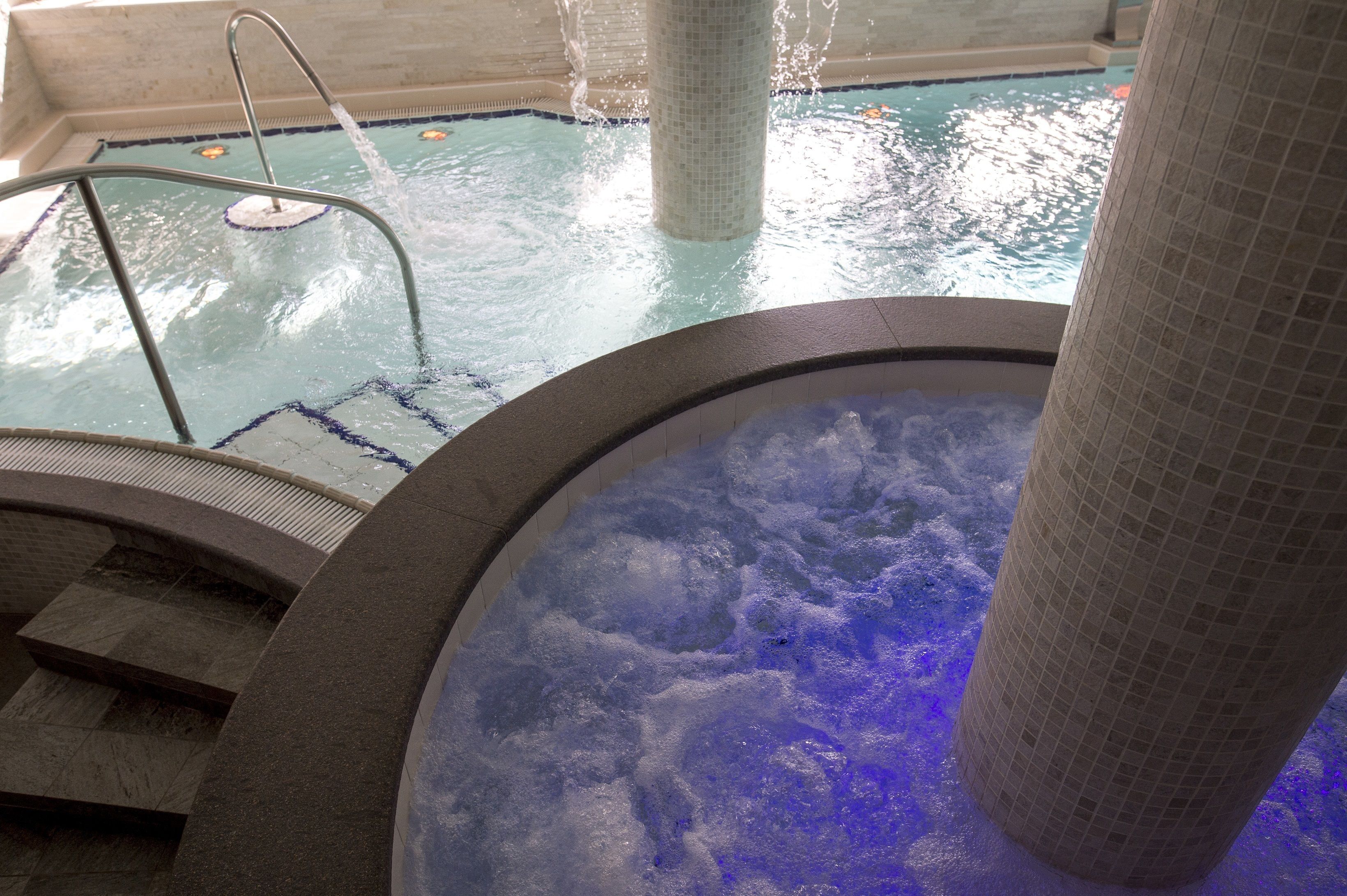 Un jacuzzi con revestimiento de azulejos y una piscina con escalera.
