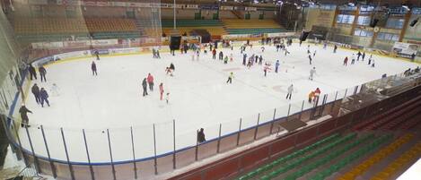 An indoor ice hockey rink with multiple levels of seating and a net in the center.