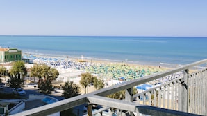 A beach with rows of umbrellas and beach chairs, a lifeguard tower, and a clear view of the ocean. - Hotel Paradiso (Senigallia)