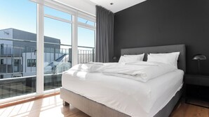 Une chambre moderne avec un grand lit, une vue sur un balcon et un mur de couleur sombre.