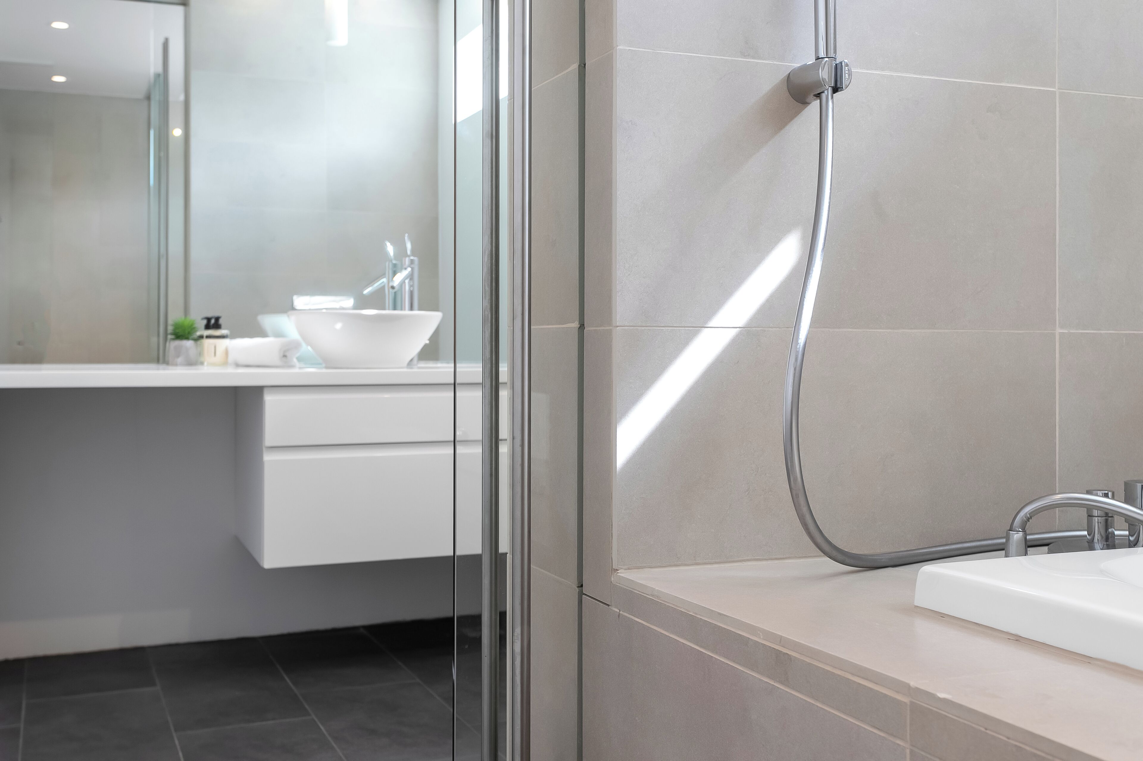 A modern bathroom with a glass shower enclosure, a white sink, and a mirror.