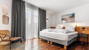 Une chambre à coucher moderne avec un lit, une chaise, une table de chevet et un tableau au mur.