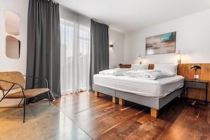 A modern bedroom with a bed, a chair, a nightstand, and a painting on the wall. - B2 Apartments by Heimaleiga (Reykjavik)