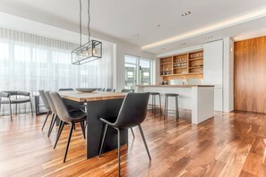 A modern kitchen with a central island, bar stools, and a dining area with chairs.