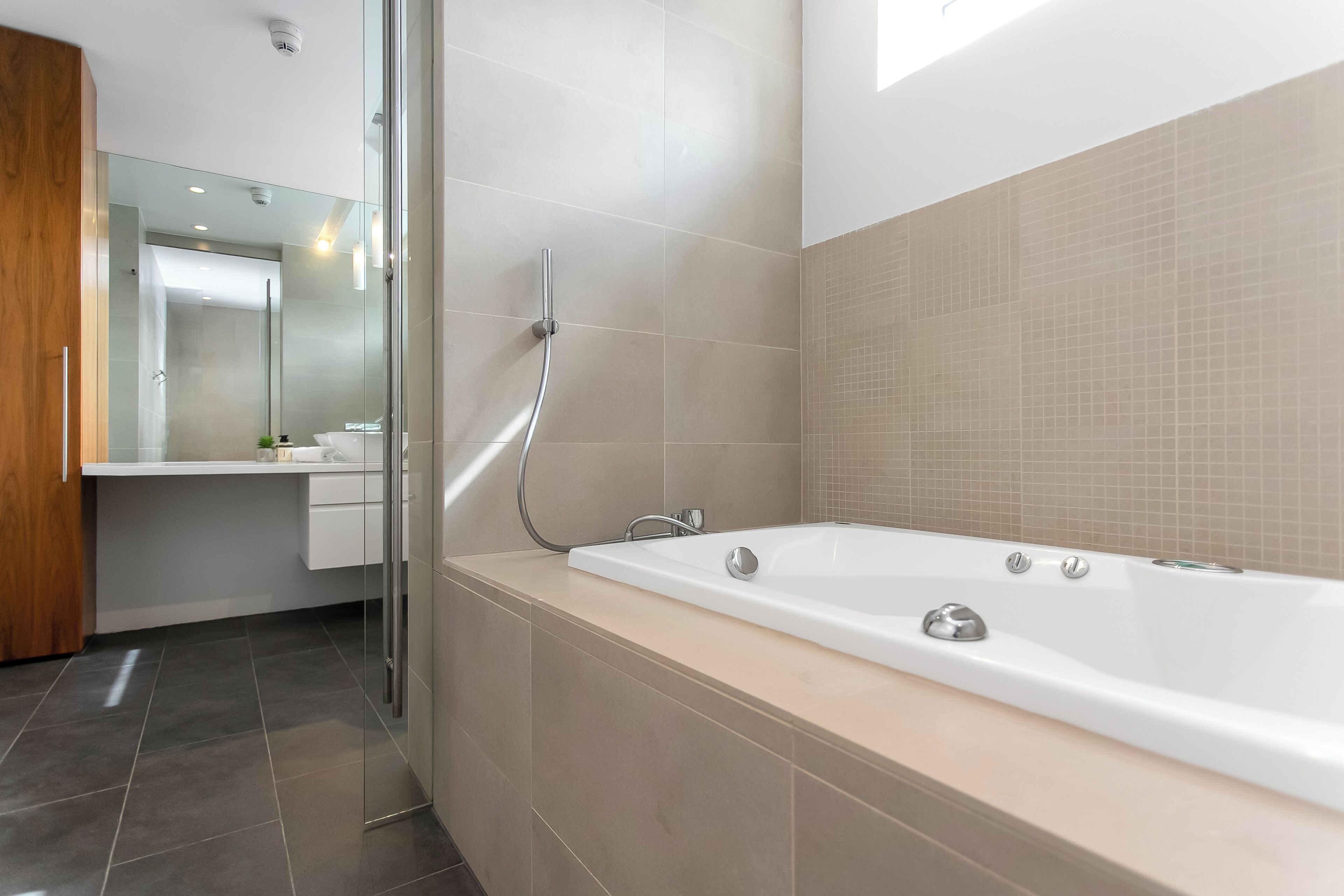 Ein modernes Badezimmer mit einer großen Badewanne, einer Duschkabine aus Glas und einem Holzschrank.