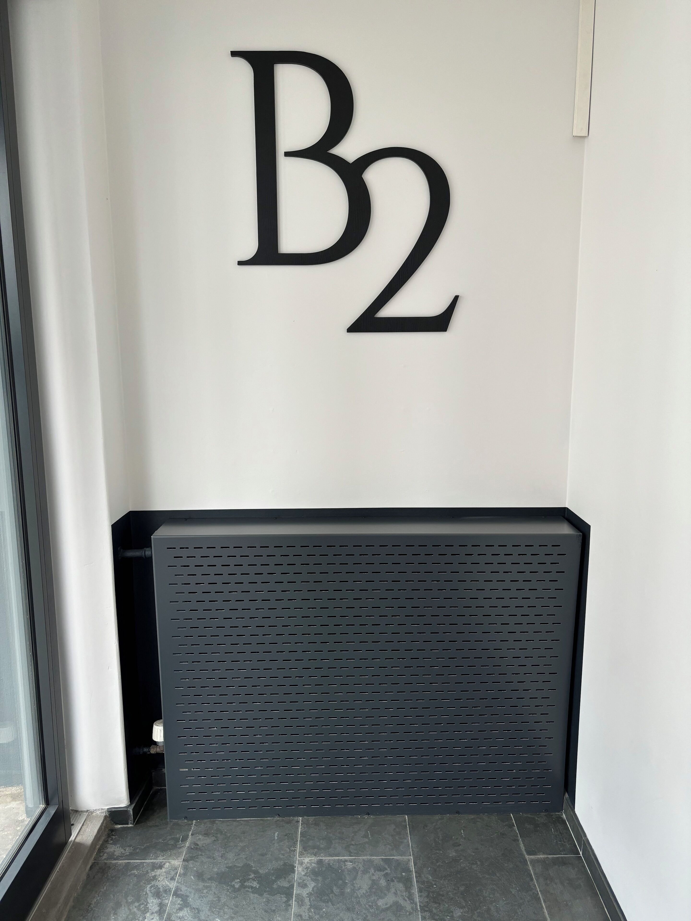 A wall with a large 'B2' sign, a black radiator, and a tiled floor.