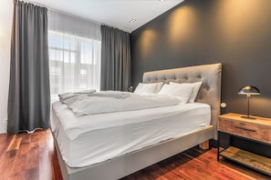 A modern bedroom with a large bed, a nightstand, and a lamp.