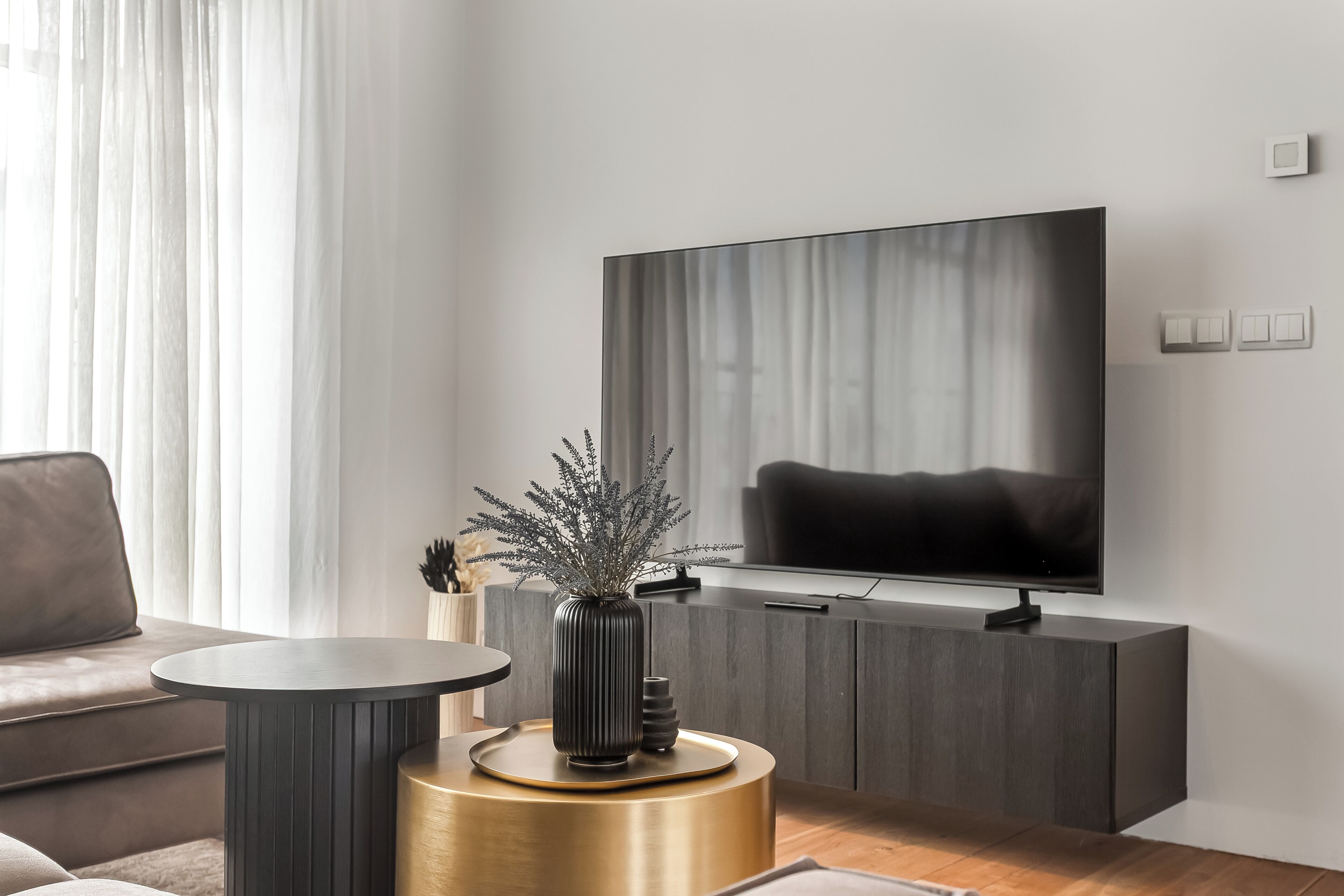 A modern living room with a sofa, a round table, a TV, and a cabinet.