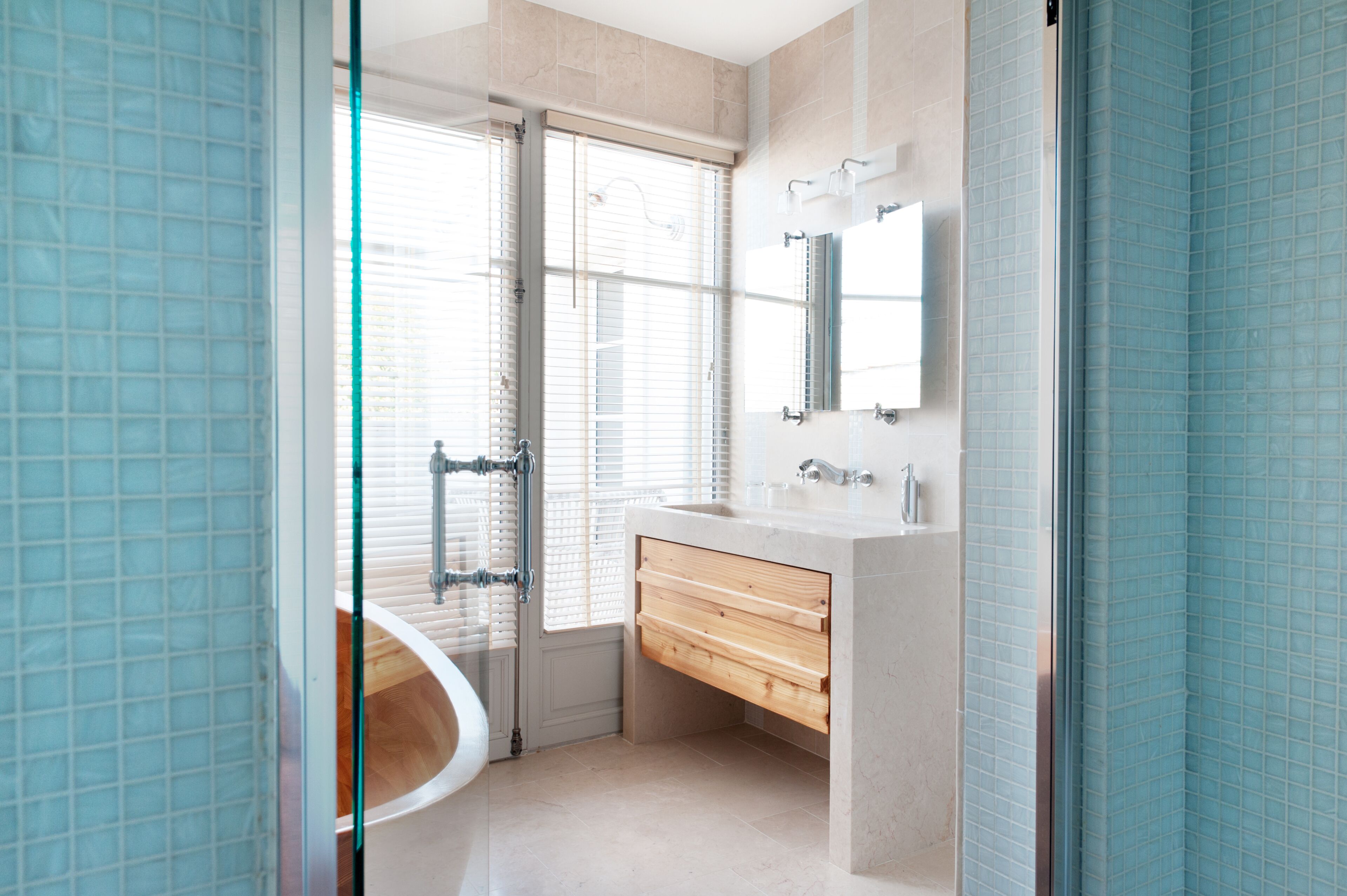 A modern bathroom with a glass shower enclosure, a freestanding bathtub, and a vanity with a mirror.