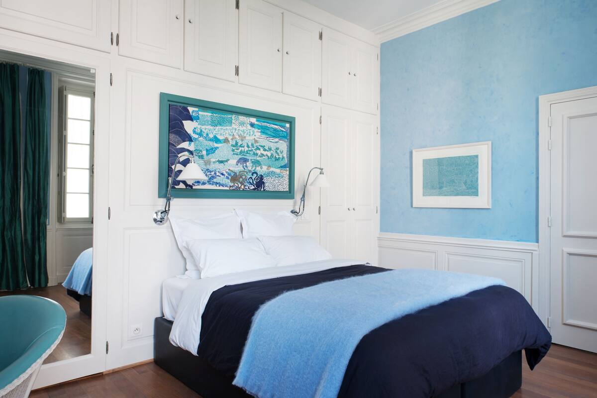 A bedroom with a bed, a painting, and a door.