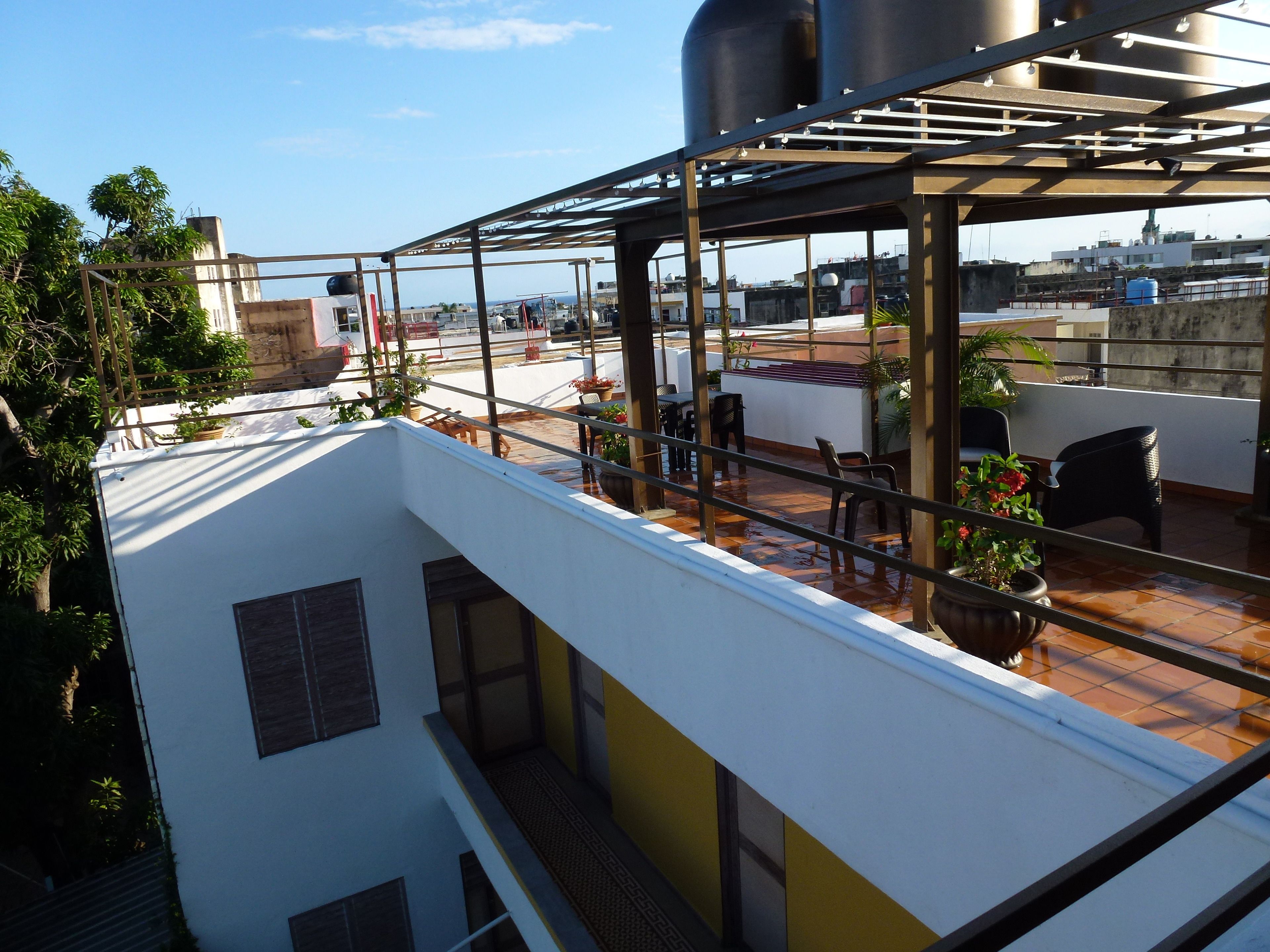 A rooftop terrace with a metal pergola, potted plants, and outdoor seating.