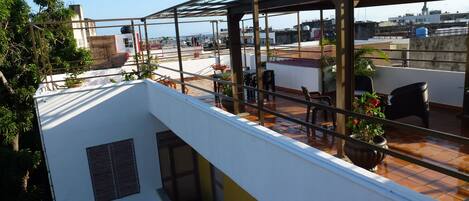 A rooftop terrace with a metal pergola, potted plants, and outdoor seating.