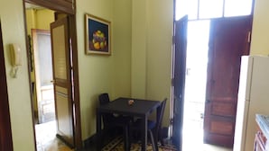 Un pequeño comedor con una mesa y sillas, suelo estampado, una puerta que da al exterior y un refrigerador.