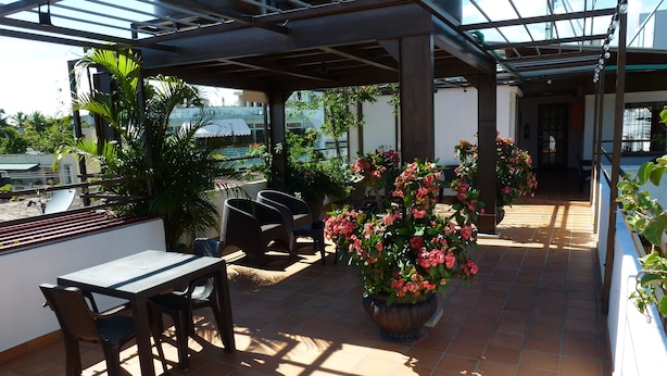 Un patio al aire libre con una zona de estar cubierta, una mesa y plantas en macetas.