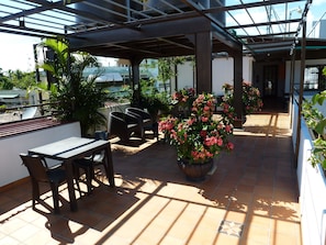 An outdoor patio with a covered seating area, a table, and potted plants. - Residencial La Fonte (Santo Domingo)