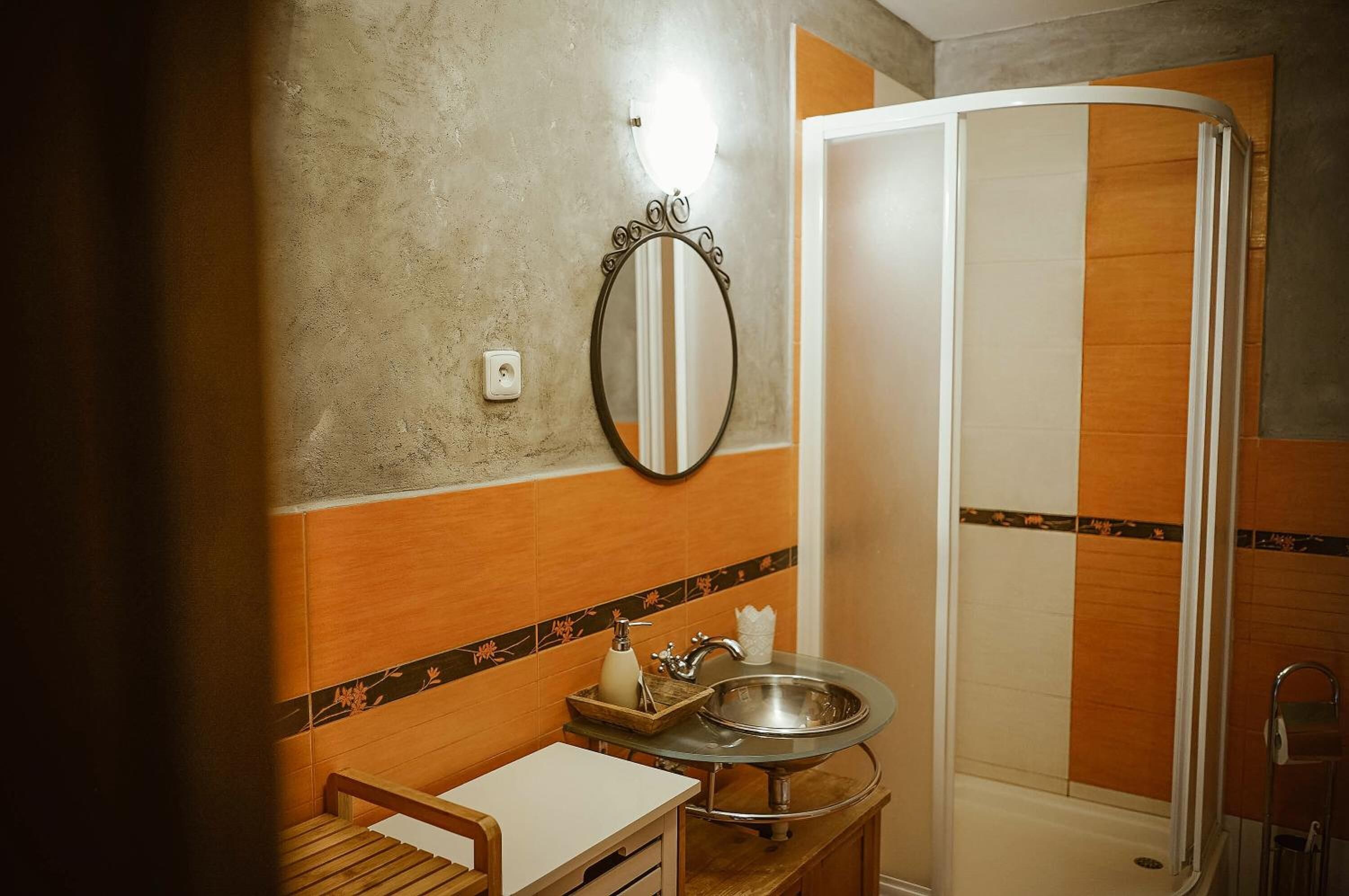 A bathroom with a sink, mirror, and shower.
