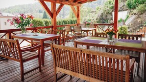 Une terrasse en bois, agrémentée de tables et de bancs, qui offre une vue sur un paysage montagneux.