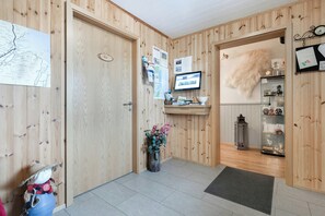 Un espace d’accueil avec des panneaux de bois, un comptoir d’accueil, un écran d’ordinateur, une carte et une plante décorative.