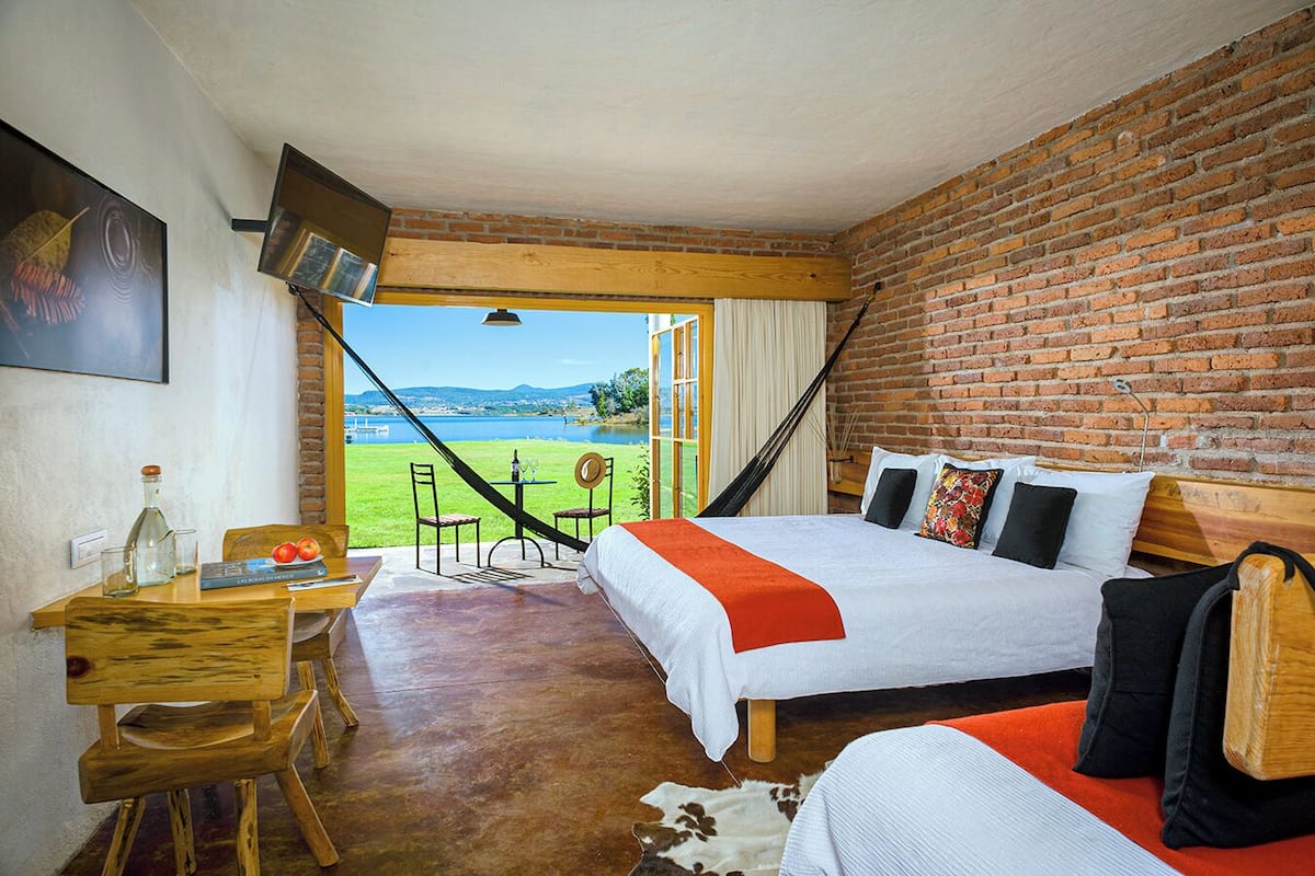 A bedroom with a large bed, a desk, and a view of a lake.