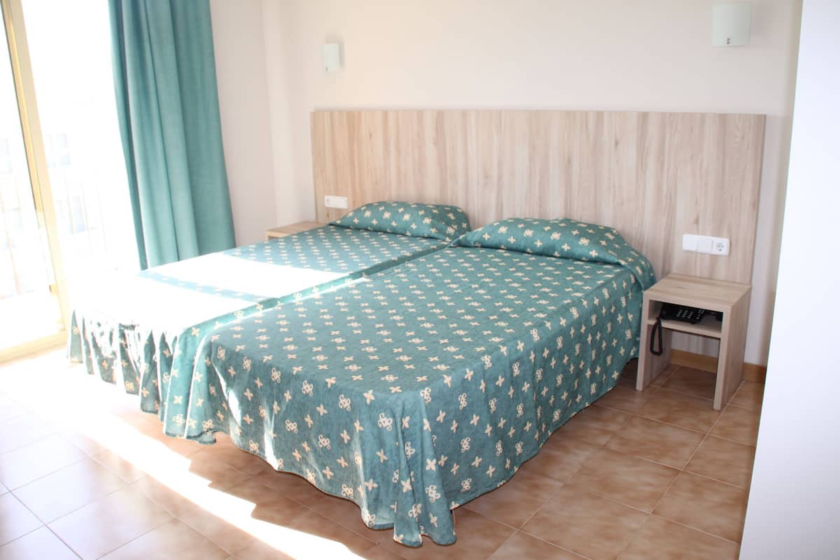 Habitación con dos camas, cabecera de madera y una mesita de noche con teléfono.