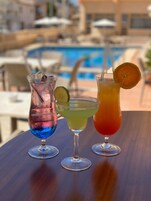 Tres cócteles sobre una mesa, con una piscina al fondo.
