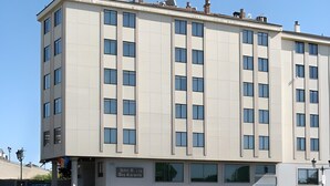 En bygning med flere etager, en flad facade, store vinduer og et skilt, der angiver, at det er et hotel.