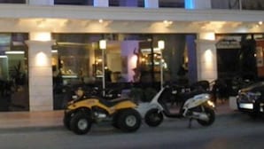 A hotel named "HOTEL VENUS MELENA" with a modern facade, multiple balconies, and a ground-level entrance with scooters parked outside. - Venus Melena (Hersonissos)