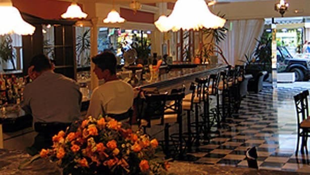 A bar area with a checkered floor, bar stools, and hanging lamps. - Venus Melena (Hersonissos)
