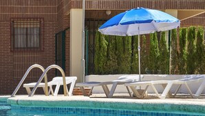 En swimmingpool med solstolar och ett parasoll.