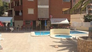 A pool area with two pools, a bar named 'BAR MARC', and outdoor seating.