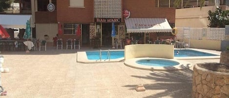 Un área de piscina con dos piscinas, un bar llamado 'BAR MARC' y mobiliario de exterior.