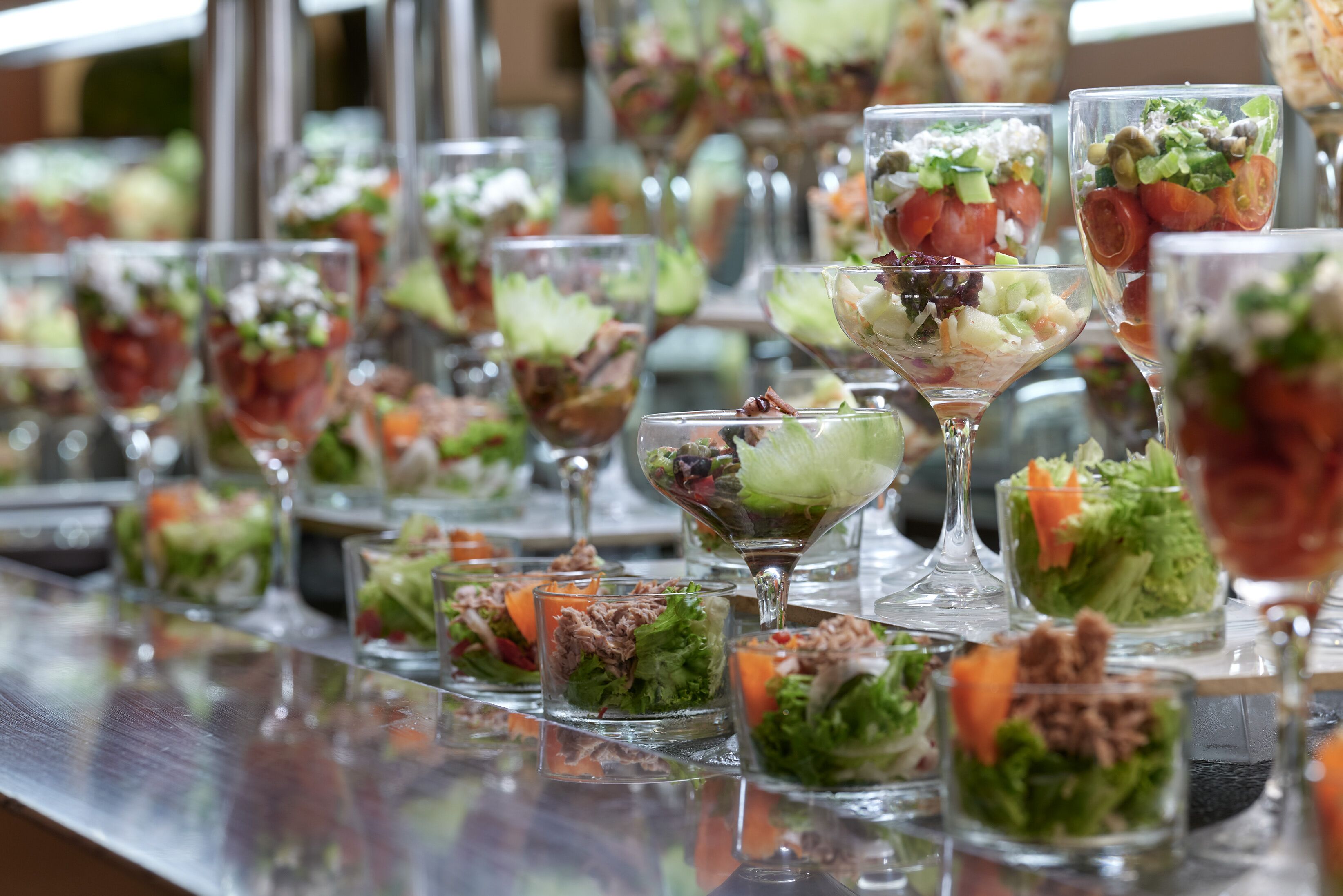 A buffet table with various glass dishes containing salads and appetizers.