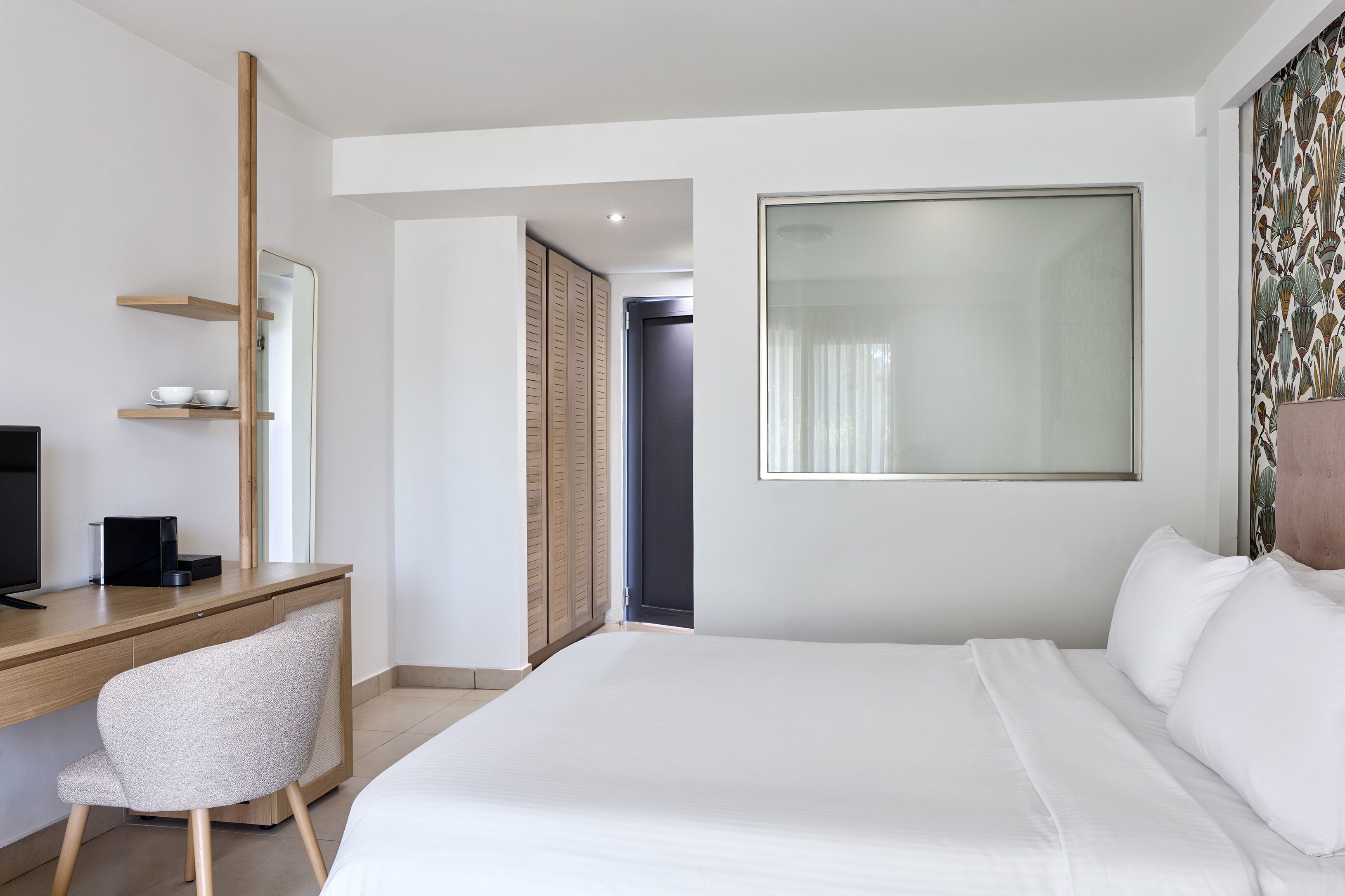 Een hotelkamer met een bed, een bureau, een stoel, een televisie en een kledingkast.