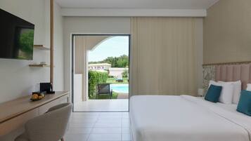 Ein Hotelzimmer mit Bett, Schreibtisch mit Stuhl, Fernseher und Blick auf Pool und Grünfläche.