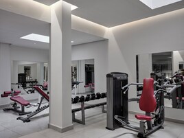 A modern gym with various exercise equipment, large mirrors, and a clean, minimalist design.