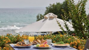 A table set with breakfast items and a glass of orange juice, overlooking the ocean. - Atlantica Eleon Grand Resort - All Inclusive (Zakynthos)