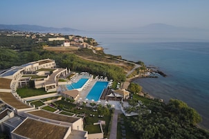 Un resort con una grande piscina, diverse camere e una vista panoramica sulla costa.