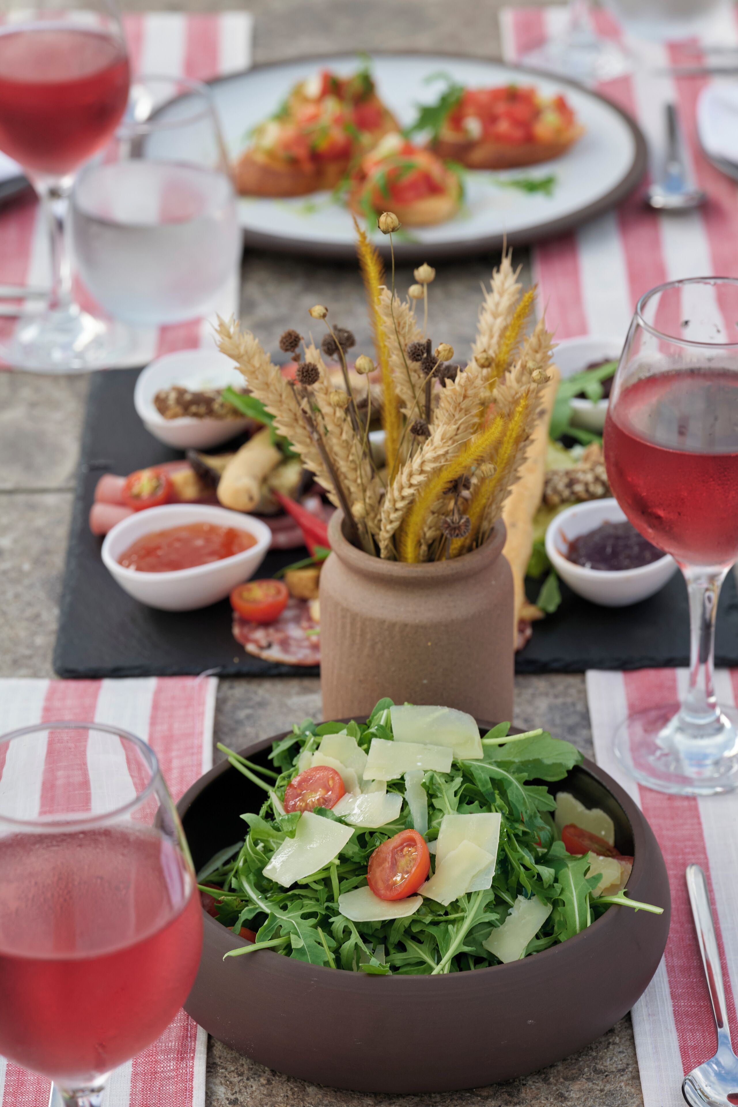 Una mesa con ensalada, copas de vino y un plato de comida.
