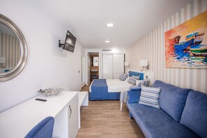A modern hotel room with a blue sofa, a white desk, and a painting of a boat on the wall. - IG Nachosol Atlantic & Yaizasol by Servatur (Mogan)