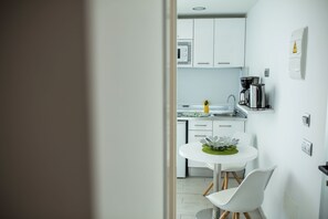 A modern kitchen with white cabinets, a coffee machine, and a small dining table with chairs. - IG Nachosol Atlantic & Yaizasol by Servatur (Mogan)
