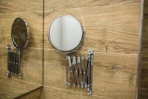 Un baño con paredes de paneles de madera, un espejo redondo y un perchero metálico.