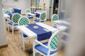 A restaurant interior with white tables and chairs, blue tablecloths, and green patterned cushions. - IG Nachosol Atlantic & Yaizasol by Servatur (Mogan)