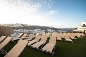 A rooftop lounge area with rows of sun loungers and a view of a residential area in the background. - IG Nachosol Atlantic & Yaizasol by Servatur (Mogan)
